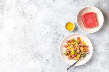 Beyaz tabakta kişniş ve mor soğanlı mango salatası tartarı.
