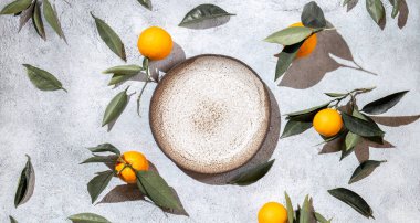 Portakal yaprakları beyaz arka planda, boş tabağın etrafında. Üst manzara, düz yatak, yaz ve sağlıklı konsept. Model