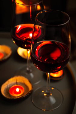 Şöminenin önünde iki kadeh kırmızı şarap. Romantik ışık