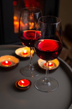 Şöminenin önünde iki kadeh kırmızı şarap. Romantik ışık