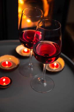 Şöminenin önünde iki kadeh kırmızı şarap. Romantik ışık