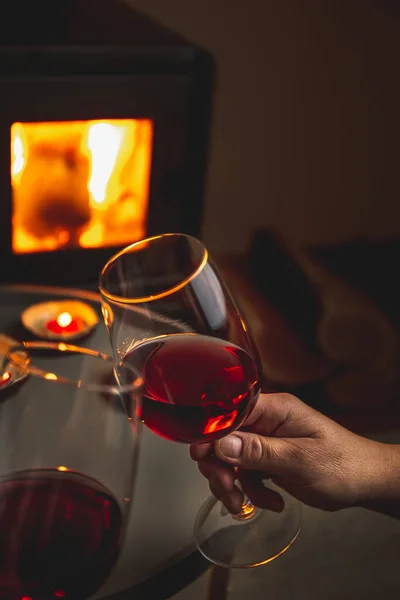 Два человека держат бокалы красного вина перед камином. Романтический свет — стоковое фото