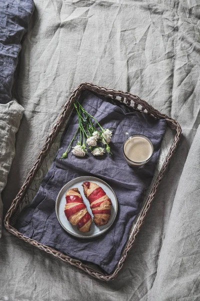 Поднос для завтрака на кровати. Круассан и кофе на бамбуковом подносе на постельном белье — стоковое фото
