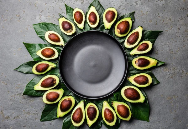 Avocado en avocado boom bladeren frame rond lege plaat. Kopieer ruimte voedsel achtergrond — Stockfoto