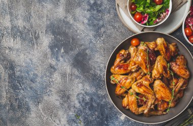 Kızarmış bbq kanatları ve domatesli yeşil salata. Üst görünüm