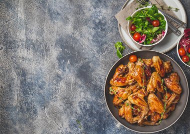 Kızarmış bbq kanatları ve domatesli yeşil salata. Üst görünüm