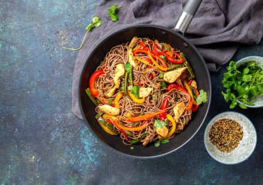 Japon karabuğdaylı soba eriştesi, tavuk ve sebzeli havuç, dolmalık biber ve lacivert arka planda yeşil fasulye.