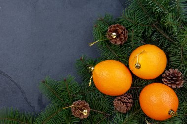 Noel arka planında çam ağacı konileri, çam ağacı dalları ve portakallar var. sıfır atık kavramı.