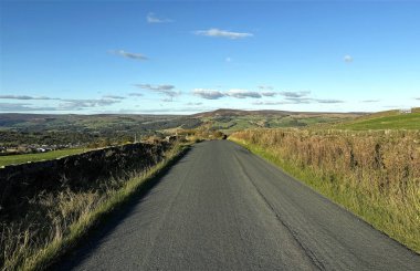 Ufka doğru açılırken Cocking Lane 'de sonbahar renkleri, açık alanlarla çevrili. Birkaç bulut açık bir gökyüzünde sürükleniyor, Ilkley, İngiltere yakınlarındaki Addingham 'da hafif bir sakinlik oluşuyor.,