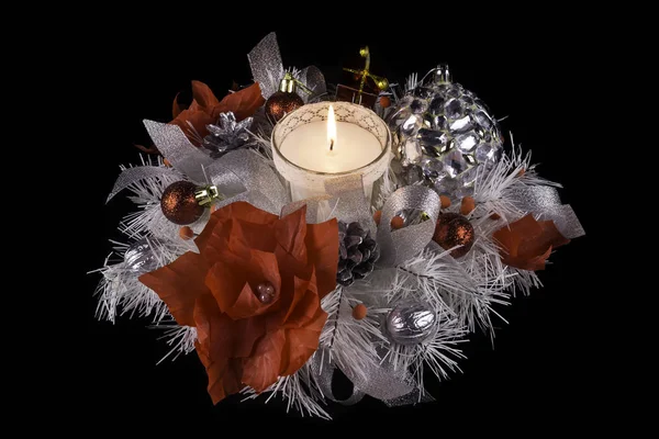 Kerstversiering met een brandende kaars gemaakt door uzelf, versierd met zilveren lint, rode bloemen, zilveren noten, dennenappels en een kunstmatige kerstboom — Stockfoto