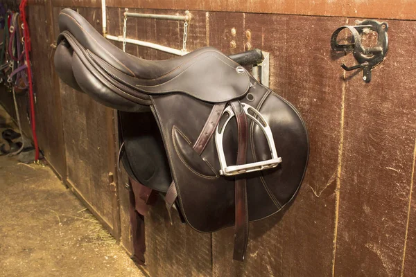 马槽托架上挂着有竞争力的深褐色皮革鞍座 — 图库照片
