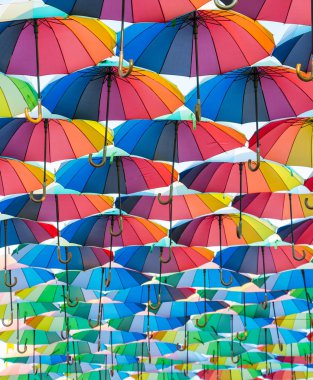 Açık şemsiye koleksiyonu, havada süzülüyor, uzaklara gidiyor, her şemsiye gökkuşağının her rengine boyanır.