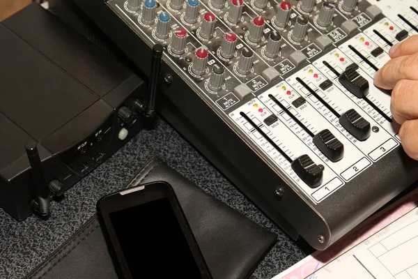 La mano humana ajusta la escala a la estación de trabajo de sonido digital junto al router y el teléfono inteligente, en el escritorio — Foto de Stock