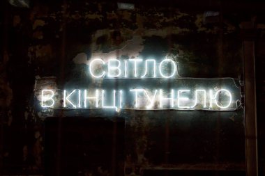 Duvarın arka planında beyaz yazı olan neon levhası.