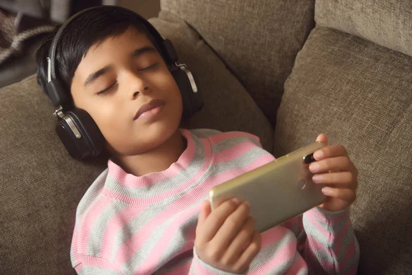 インドの若いです男の子はヘッドフォンで音楽を聞き 携帯電話を保持 — ストック写真