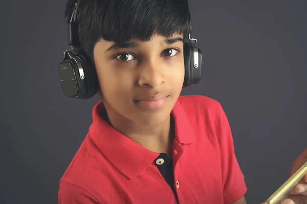 Indian young boy listen music with headphone and holding mobilephone