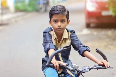 Hintli küçük çocuk bisiklet sürmenin tadını çıkarıyor.