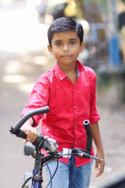 Hintli küçük çocuk bisiklet sürmenin tadını çıkarıyor.
