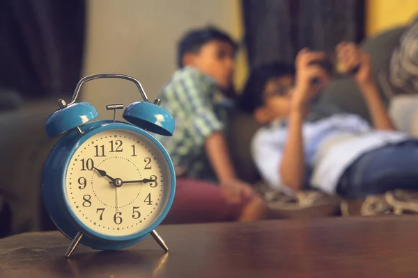 Indian Friends playing video game on smart phone. Alarm-clock is in front of them
