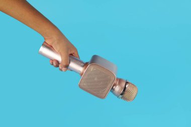 Hoparlörle el ele tutuşan mavi dişli mikrofon.