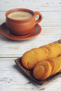 Tahta masada tereyağlı bisküvilerle bir fincan çay.
