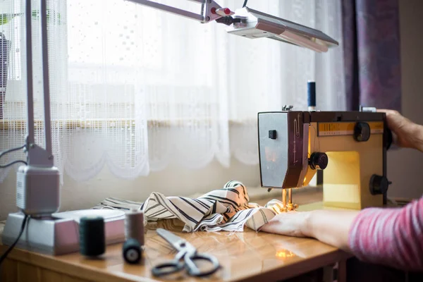Las manos de la mujer usando la máquina de coser en una fabricación de costura, proceso de costura — Foto de Stock