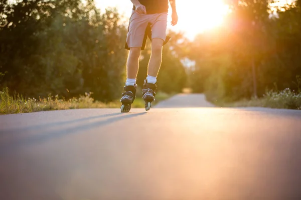 在夏日美丽的落日、生活方式和体育理念下，年轻人喜欢在自行车道上滑旱冰 — 图库照片