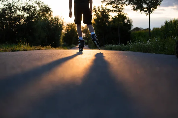 Jovem desfrutando de patinação no caminho da bicicleta durante o lindo pôr do sol de verão, estilo de vida e conceito de esporte — Fotografia de Stock