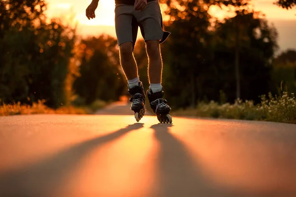 Jeune homme sur les patins à roulettes pendant le beau coucher de soleil d'été, concept de sport, patinage à roulettes, style de vie et concept de sport — Photo