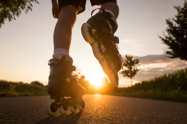 在夏日美丽的落日、生活方式和体育理念下，年轻人喜欢在自行车道上滑旱冰 — 图库照片
