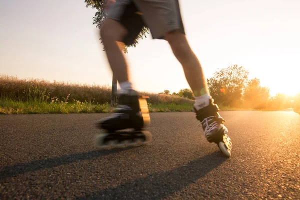 Młody człowiek cieszący się rolkami na ścieżce rowerowej podczas pięknego letniego zachodu słońca, stylu życia i koncepcji sportu — Zdjęcie stockowe