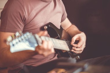 Profesyonel, siyah elektro gitar, müzik aleti, eğlence, yaşam tarzı çalan genç adamın elini kapatıyoruz.