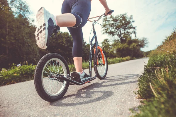 Söt ung brunett kvinna rida på en push, sparka sport på en cykelväg under härlig sommar solnedgång, livsstil koncept — Stockfoto
