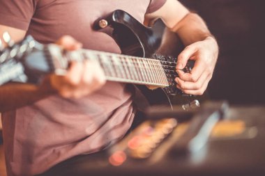 Profesyonel, siyah elektro gitar, müzik aleti, eğlence, yaşam tarzı çalan genç adamın elini kapatıyoruz.
