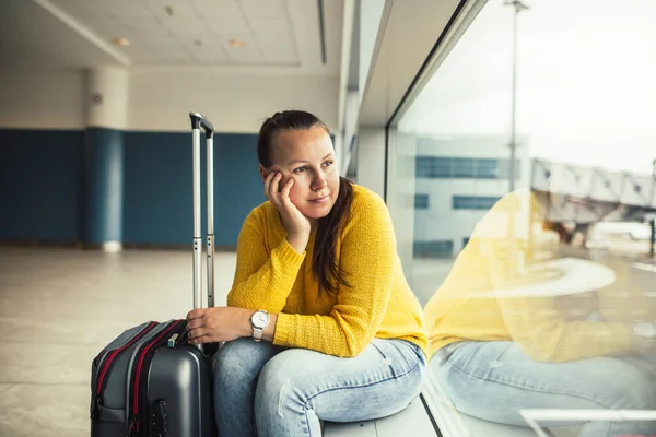Mulher morena muito jovem à espera de voo atrasado no aeroporto, olhando cansado, conceito de transporte — Fotografia de Stock