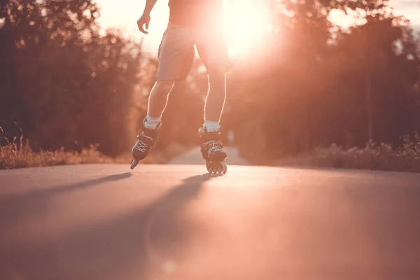 Jovem nos patins durante o lindo pôr do sol de verão, conceito de esporte, patinação em patins, estilo de vida e conceito de esporte — Fotografia de Stock