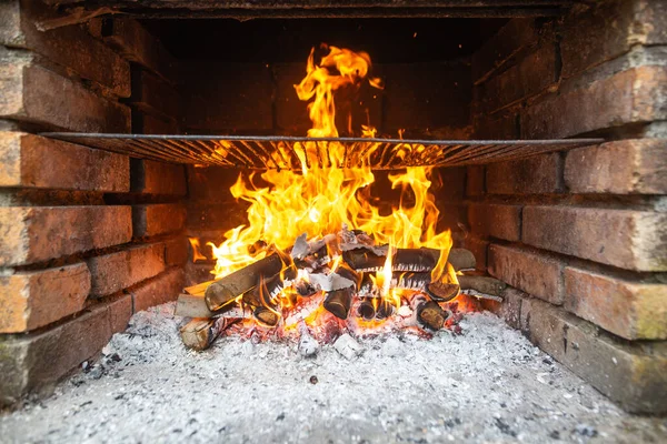 Aquecimento da grelha, chamas ardentes enormes sobre a grelha, brasas e faíscas de fogo, queima de carvão de madeira — Fotografia de Stock