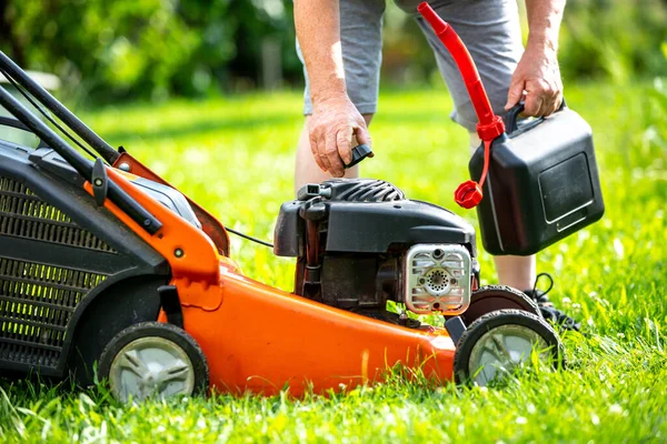 Büyük bahçesinde çim biçme makinesine yakıt dolduran adam, bahçe konsepti.