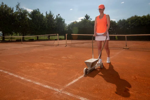 Kvinnlig tennisspelare förbereder en lera tennisbana innan hennes match, sport koncept — Stockfoto