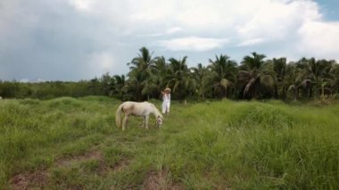 Elinde ananas olan, beyaz elbiseli ve şapkalı bir kız.