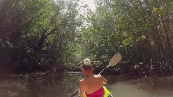 Dívka plave v kajaku s vesly v džungli — Stock video