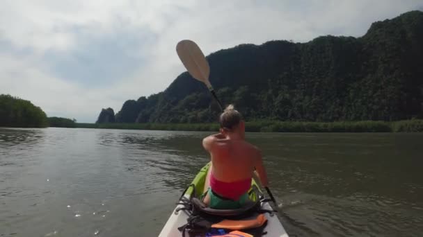 Una chica está nadando en un kayak de mar con remos entre la selva — Vídeo de stock