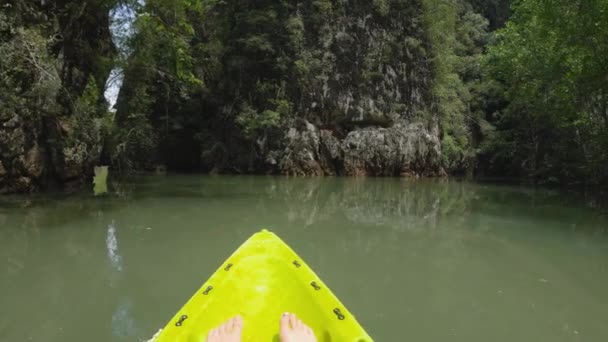 La fille fait du kayak parmi les rochers et se repose les jambes droites — Video