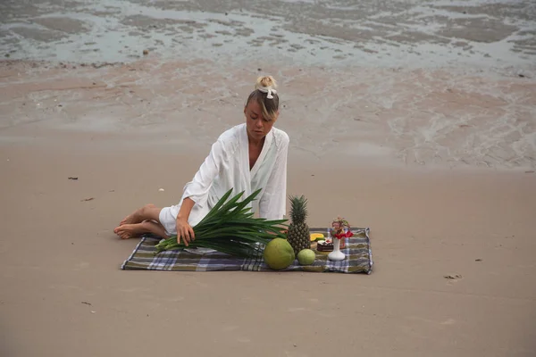 Chica en vestido blanco en la playa para un picnic con frutas exóticas —  Fotos de Stock