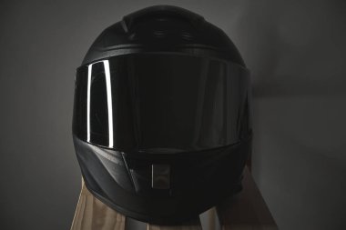 Gri arka planda kapalı güneşliği olan siyah motosiklet kaskı.