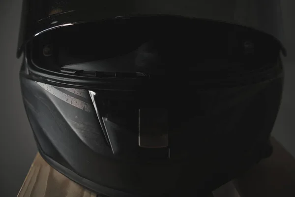 Black motorcycle helmet with a closed visor on a gray background