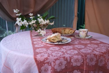 Elmalı turta, dondurma ve kahve, masanın üstünde. Vazodaki çiçekler.