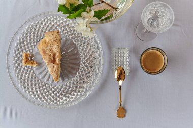 Elmalı turta, dondurma ve kahve, masanın üstünde. Vazodaki çiçekler.