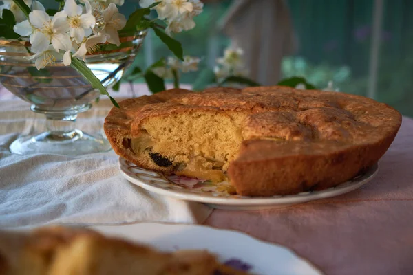 Tarte aux pommes est dans l'assiette sur la table à côté du vase et des fleurs — Photo