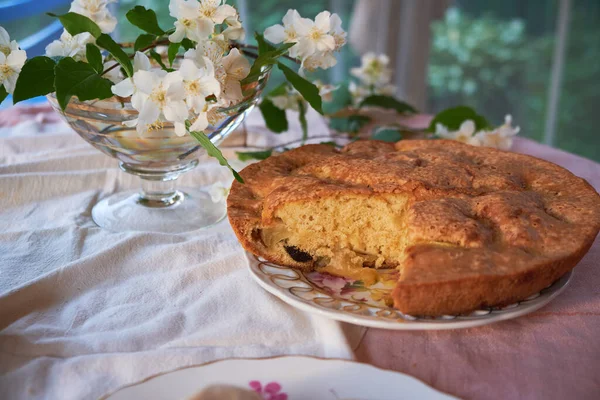 Tarte aux pommes est dans l'assiette sur la table à côté du vase et des fleurs — Photo